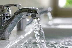 running bathroom faucet with water almost filling the entire sink